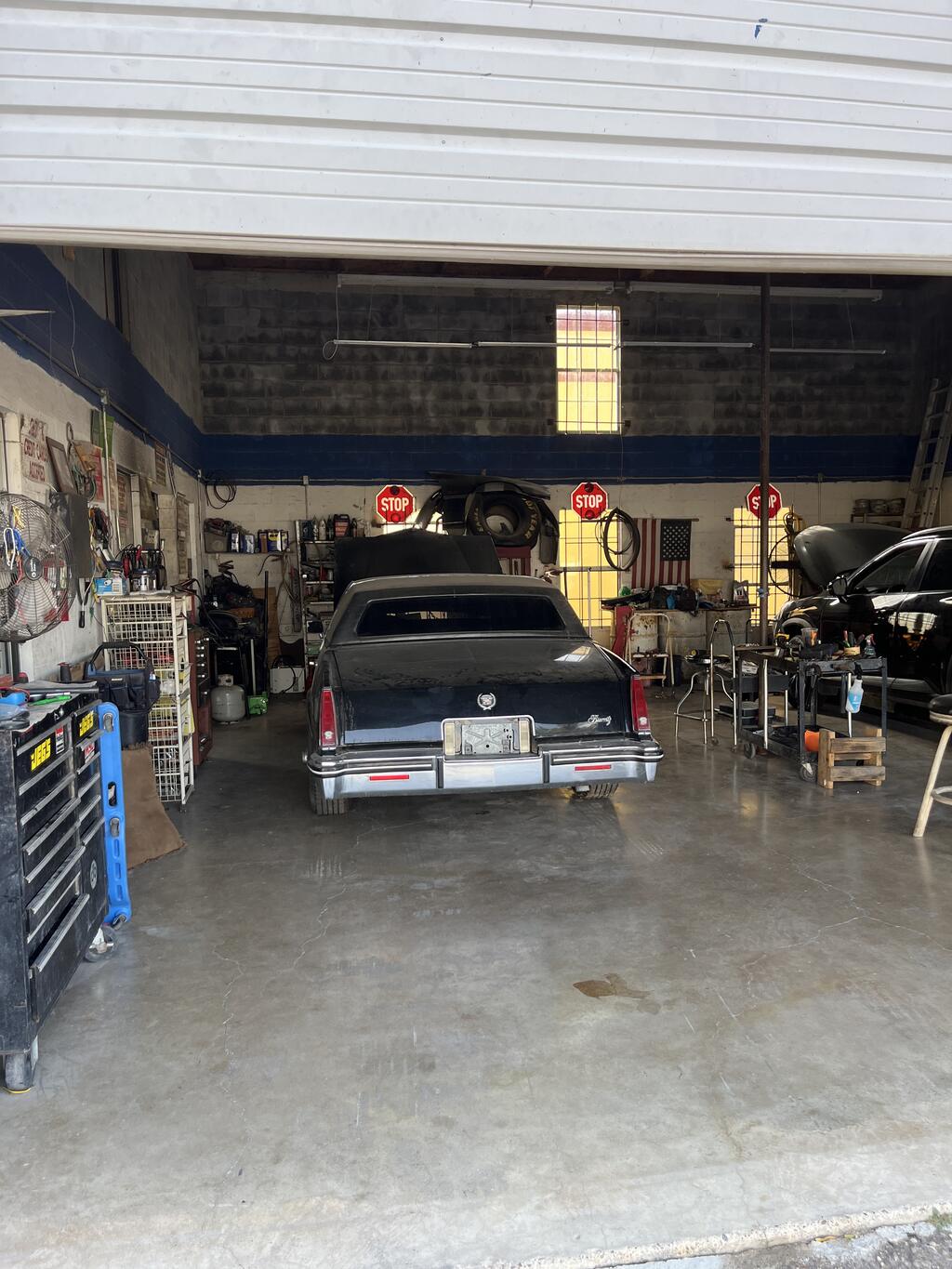 Left shop bay seen through the overhead door, with concrete floor and workbench area